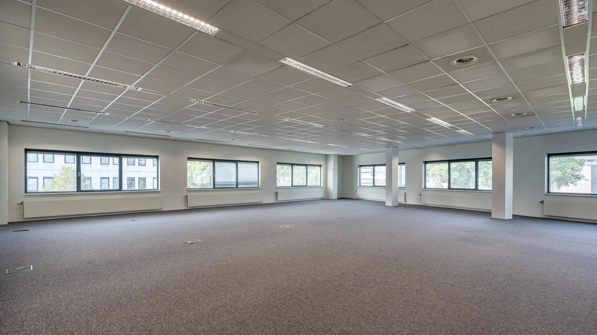 Leegstaand en licht kantoorruimte aan de Rivium Boulevard met grote ramen en systeemplafond.